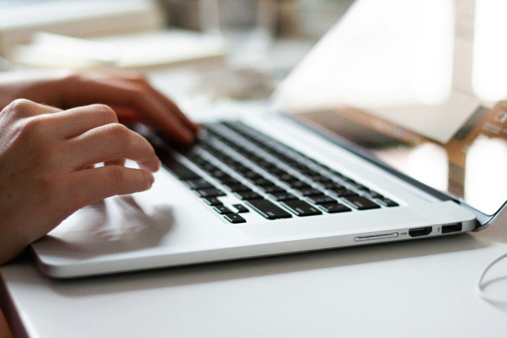 Close-up of hands typing on a laptop keyboard