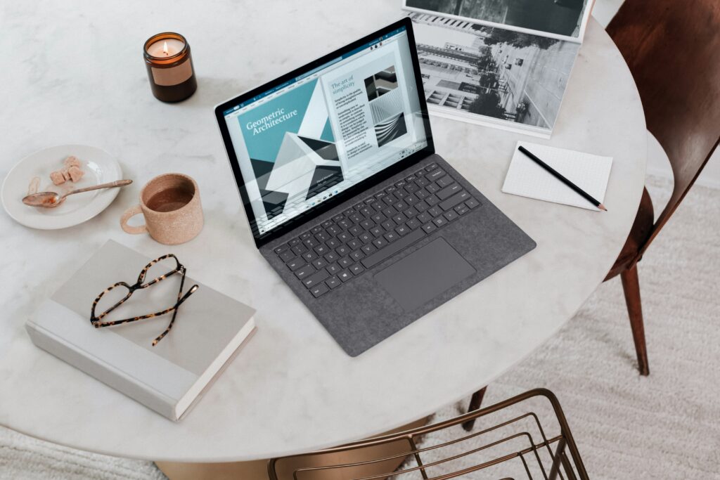 Flat lay of a laptop, coffee, glasses, and photos on a table