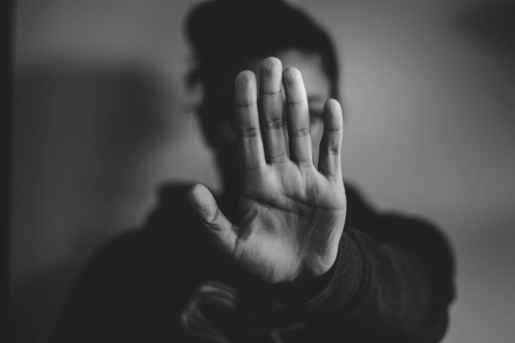 Black and white photo of a raised open palm in a stop gesture
