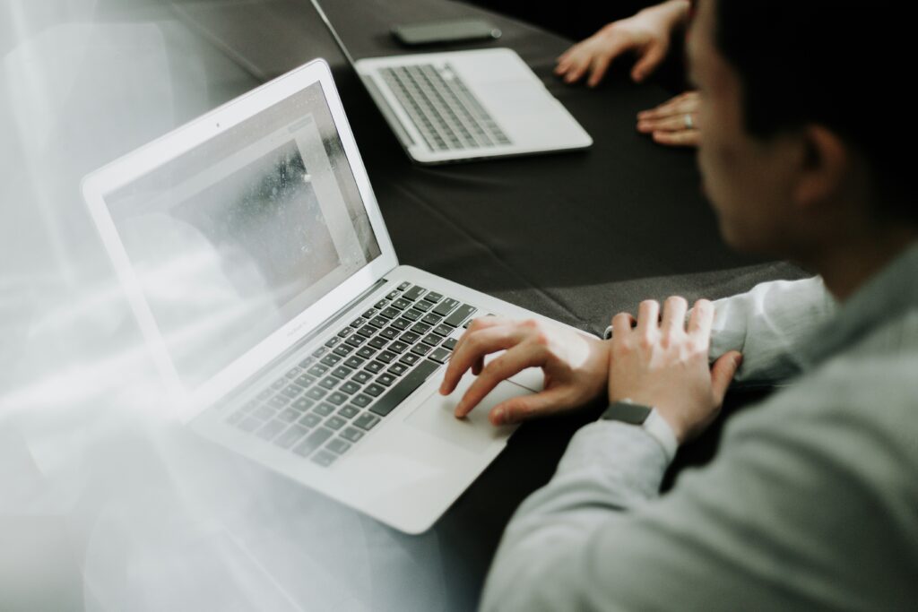 Two people sitting across from each other, each using a laptop