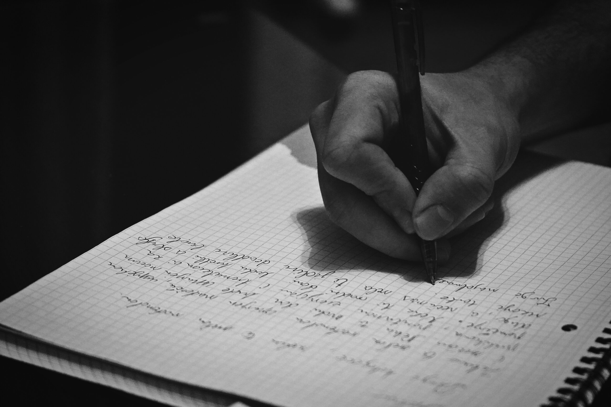 Black and white photo of a hand writing in a notebook