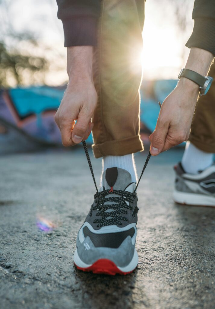 Person tying running shoe laces outdoors in the morning