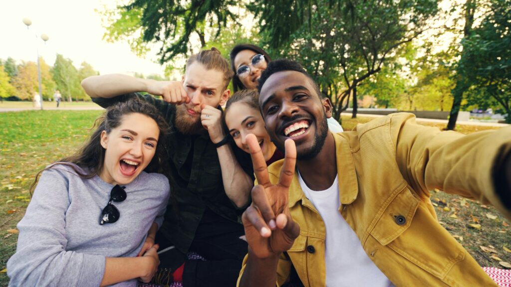 Group of five friends laughing together outdoors in a park