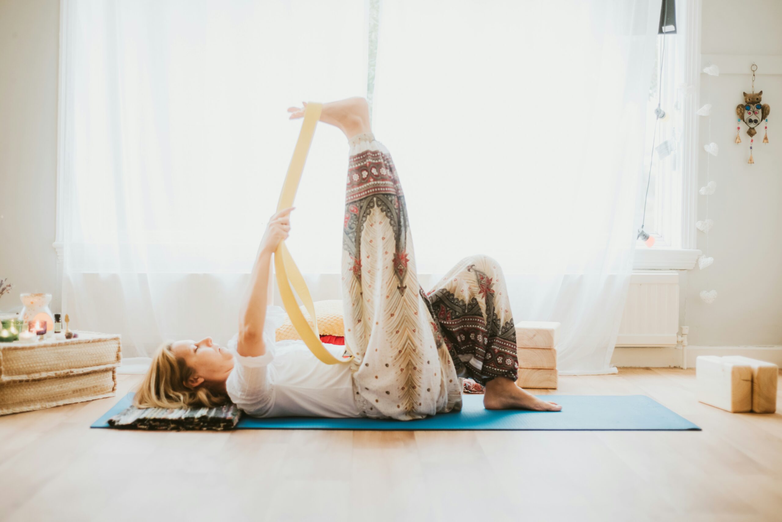 Woman stretching with a yoga strap on a mat at home