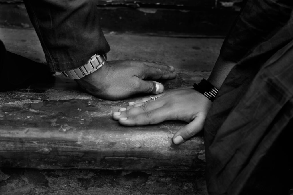 Black and white close-up of two hands resting near each other on a wooden surface