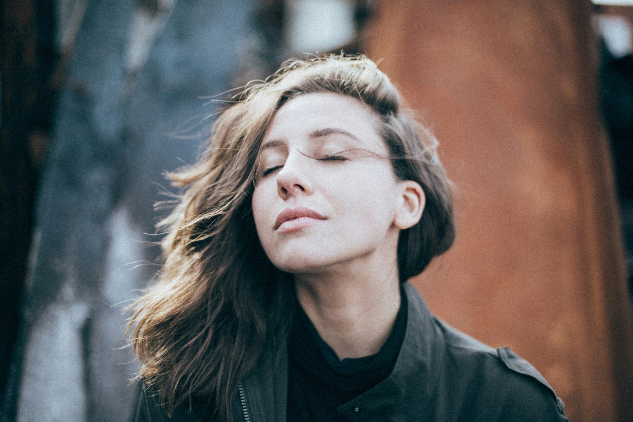 Person with eyes closed taking a calm, deep breath outdoors