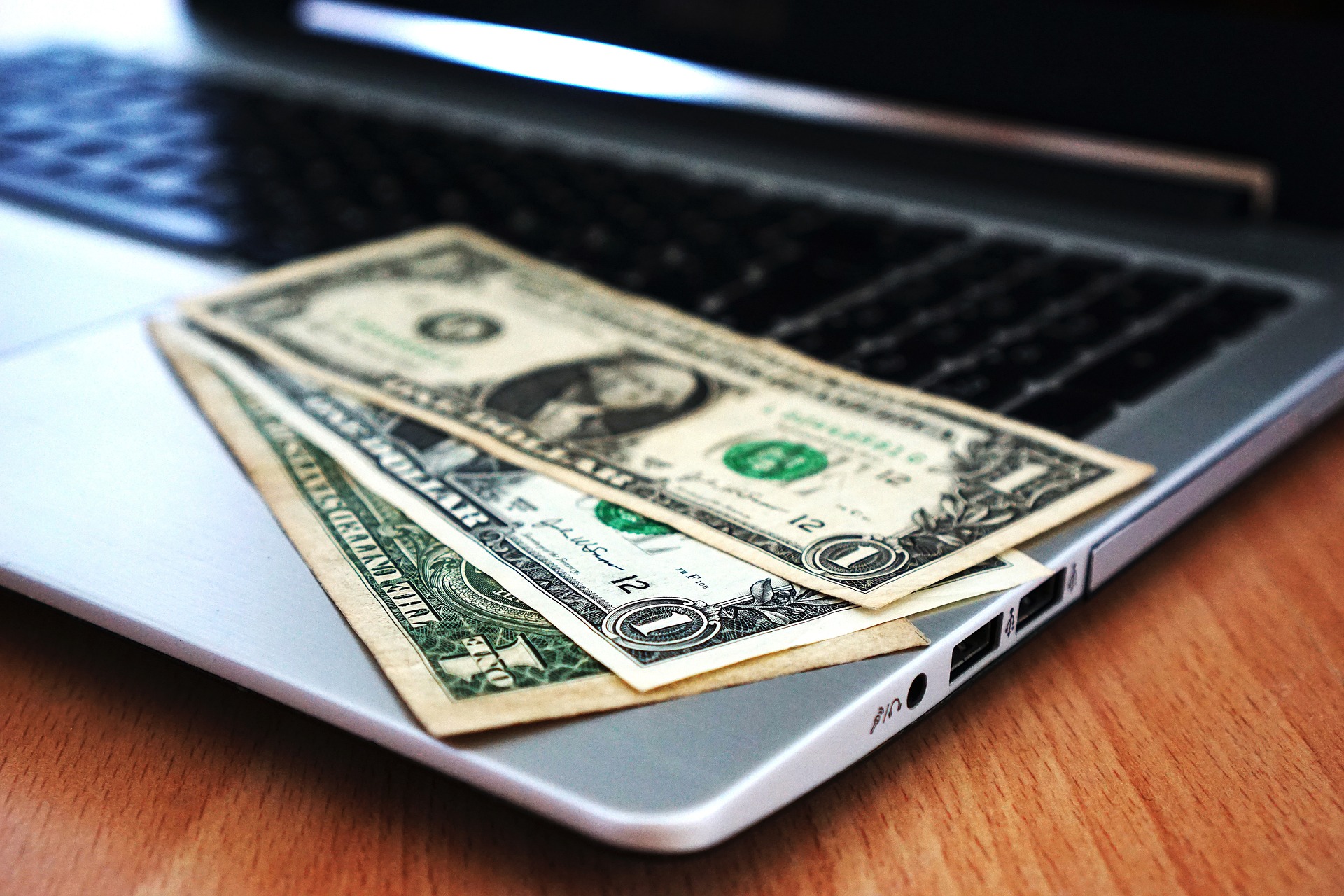 dollar bills resting on a laptop keyboard