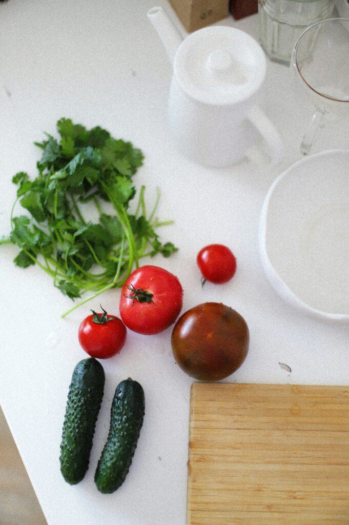 Fresh vegetables including tomatoes, cucumbers, and cilantro on a kitchen counter