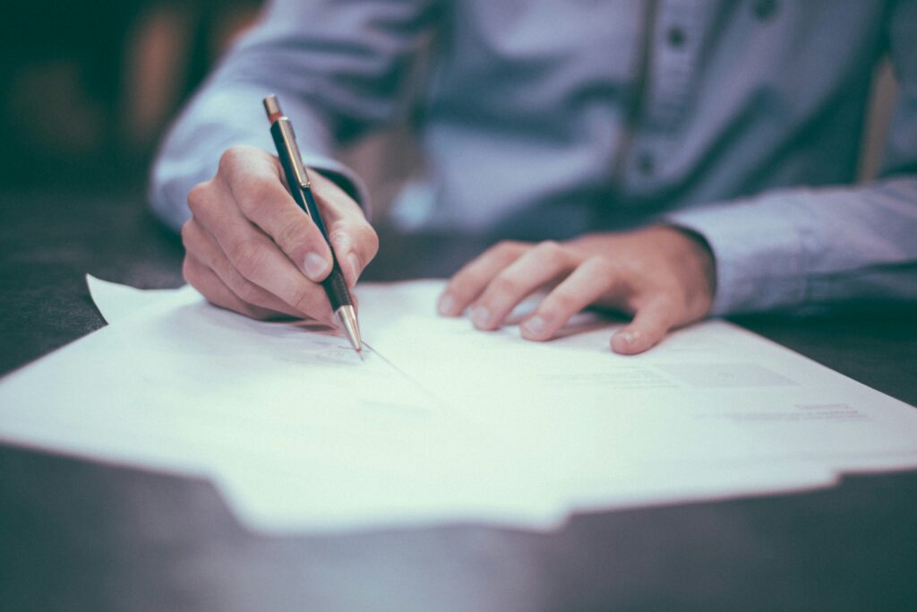 person signing a document with a pen