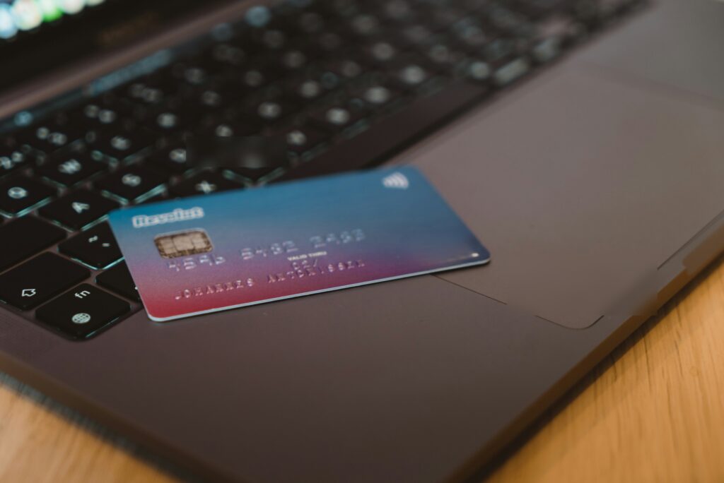 hands holding a credit card near a laptop